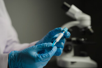 Scientist or medical in lab coat holding test tube with reagent, Laboratory glassware containing chemical liquid, Microscope, Biochemistry laboratory research