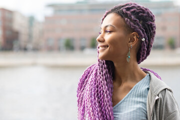 portrait of a modern african american woman outside, girl with curly colored hair with nose piercing on the background of the city - obrazy, fototapety, plakaty