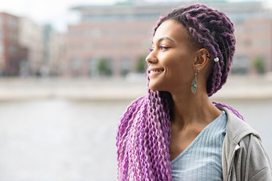 portrait of a modern african american woman outside, girl with curly colored hair with nose piercing on the background of the city
