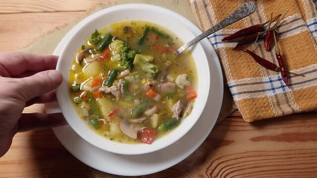 Hot vegetable soup with mushrooms in bowl on wooden table