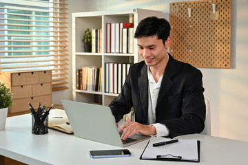 Obraz premium Photo of smiling adult male manager typing business email on laptop computer. Business and technology concept