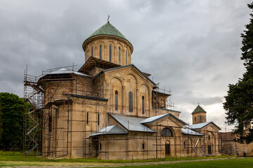 Fototapeta na wymiar Gelati Monastery, medieval monastic complex near Kutaisi, Georgia founded by King David IV, view with scaffolding during restoration process, dark cloudy sky.