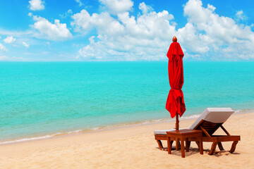 Red closed umbrella, empty deck chair, table, folding solar parasol, sun lounger, wooden chaise...
