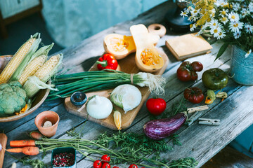 table on veranda of country village house with different vegetables, eco-friendly food from garden, autumn harvesting corn, pepper, tomatoes, cucumbers, kohlrabi, cabbage
