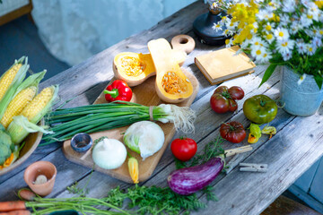 table on veranda of country village house with different vegetables, eco-friendly food from garden, autumn harvesting corn, pepper, tomatoes, cucumbers, kohlrabi, cabbage