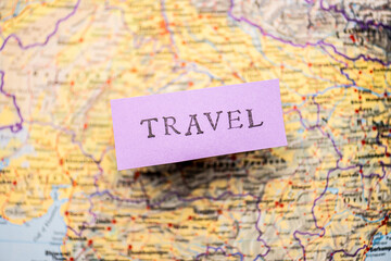 Travel stencil text on purple paper over a map.