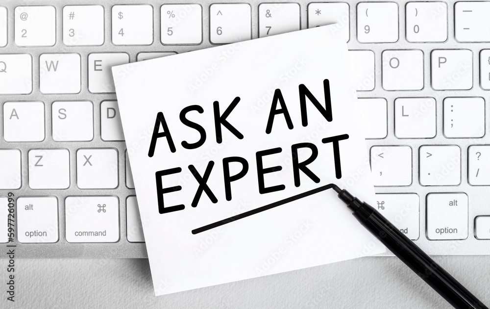 Poster white paper with text ask an expert lying on the keyboard