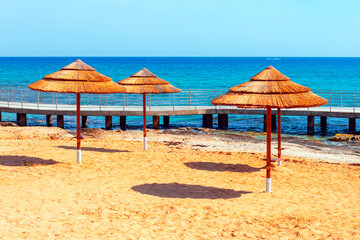 Straw sun umbrellas at tropical beach . Musan beach in Cyprus