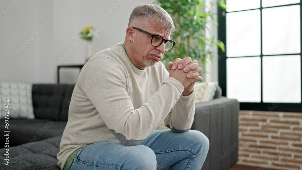 Sticker Middle age grey-haired man stressed sitting on sofa at home