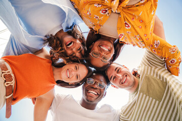 Low angle view of a group of five multiracial teenagers smiling and looking down at camera...