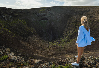 Naklejka premium Blonde woman looking at the volcano's crater Fuerteventura, Canary Islands