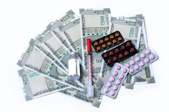 Medical concept. pills and syringe and medicine vial over indian banknotes on white background with copy space.
