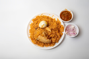 Traditional Indian spicy food hot chicken biryani with egg, raita and onion on plate on white background.