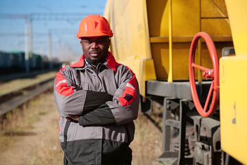 Fototapeta premium Railroad man in uniform and red hard hat look at the camera