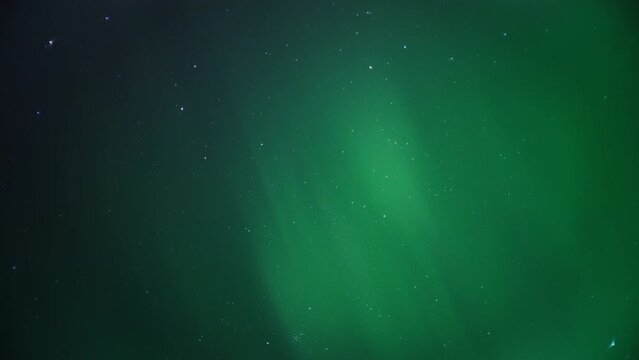 Rays of Northern Lights lighting up the night sky full of stars. Timelapse. 