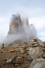 le tre cime di lavaredo emergono tra ometti segnavia e nebbie