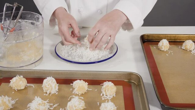 Scooping cookie dough into the baking sheet to bake coconut cookies.