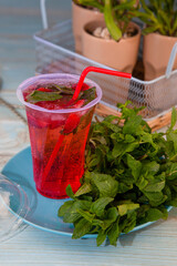 Summer mint strawberry refreshing cocktail mojito with ice in plastic glass with straw. Carbonated mineral water. Glass for drinks. Lemonade at the bar menu background. Classic sparkle drink