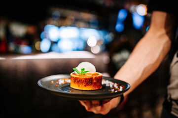 waiter hand hold chocolate fondant cake with ice cream and caramel