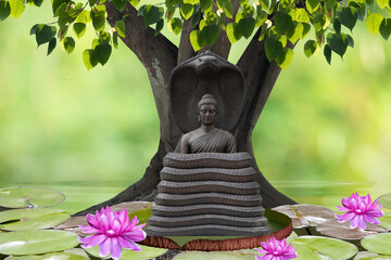 Buddha statue sitting under the bodhi tree on nature background.