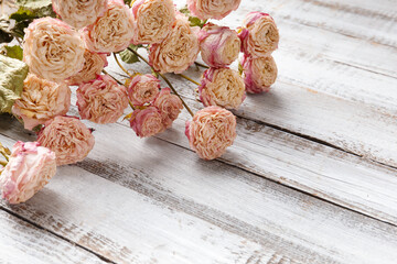 Dry roses on a light wooden background.