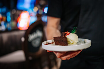 waiter hand hold Chocolate Brownie cake with Vanilla Ice Cream