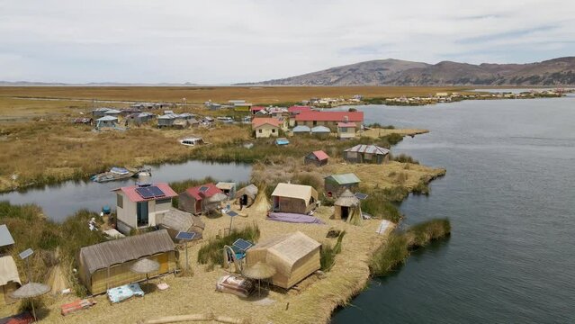 4K Aerial Drone Orbit Arc around Uros Islands at Lake Titicaca near Puno, Peru. Authentic Boat, lake, reeds, and floating islands visible.