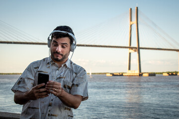 Hombre escuchando música con su celular en la rivera del Río Paraná, en Rosario