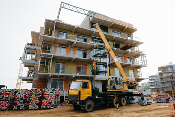 Construction crane on a truck and building materials at the construction site of a modern house with a luxury apartment