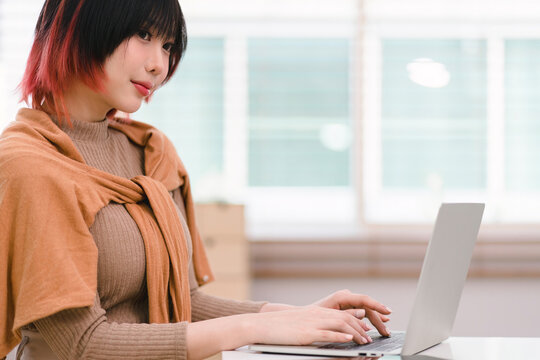 A creative female ux ui designer is concentrating on the computer screen to design, code, and program a mobile application from a prototype and wireframe layout in the office.