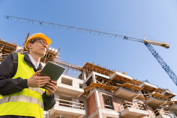 Engineer with a digital tablet on the background of a building under construction	