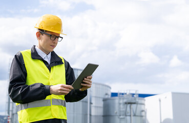 Engineer with digital tablet on a background of gas tanks	