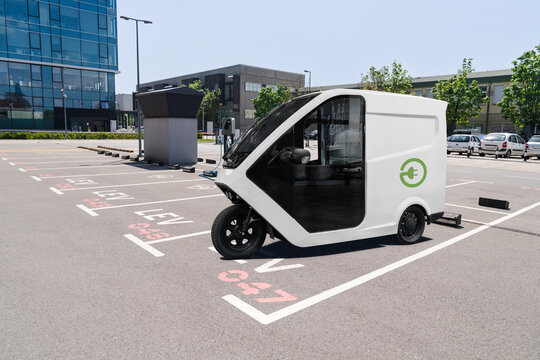 Electric tricycle scooter with charging station on a parking lot for LEV - light electric vehicles	