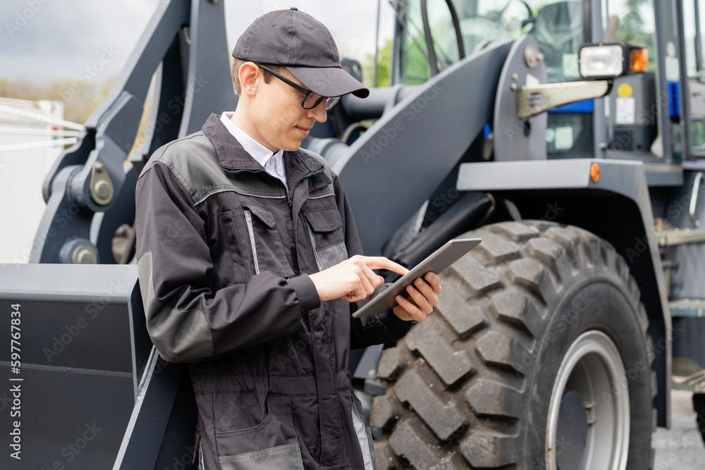 Poster Serviceman with digital tablet on a background of the tractor 