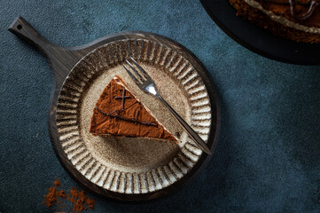 Plate with slice of tasty homemade chocolate cake on blue background. Space for text. Cake flatlay. Piece of chocolate cake