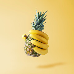 Creative fruit concept. Hand in the form of bananas holding a pineapple.
