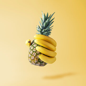 Naklejki Creative fruit concept. Hand in the form of bananas holding a pineapple.