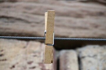 Wäscheklammer aus Holz an grauer Wäscheleine vor alter braungrauer Hausfassade 