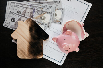 Lost of savings and destruction of real estate concept. Broken piggy bank and a burn house on an...