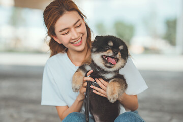 Happy asian woman playing with dog together in park outdoors