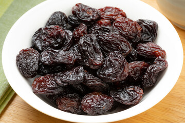 White bowl with large black flame raisins from Chile close up   