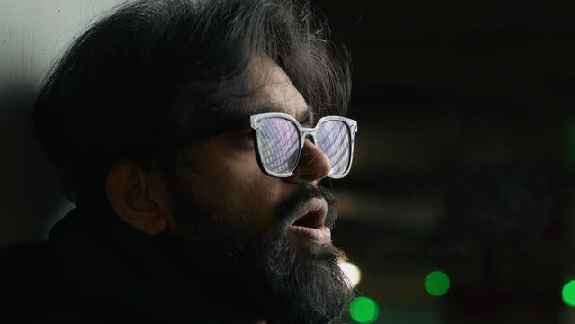 Close up Indian bearded man in glasses at dark parking lot underground in night evening cold Arabian stressed sad guy Muslim male exhale steam frozen breath frosty smoke cool temperature flue disease