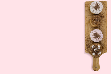 Cakes sprinkled with chocolate on a culinary board, on pink isolated, top view, space for text