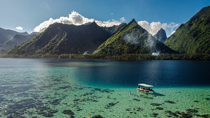 Photo de Tahiti en Polynésie Française. Vue d'un drone avec l'océan et les montagnes. Bateau de tourisme faisant visiter le littoral. - obrazy, fototapety, plakaty