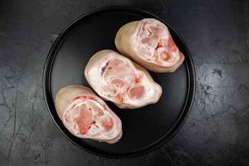Pork knuckles steaks on a black plate on a black background, top view