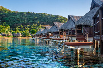Bungalow sur l'eau en Polynésie française avec une eau turquoise et du corails. Lieu de tourisme paradisiaque. - obrazy, fototapety, plakaty