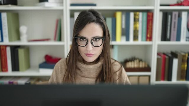 Beautiful hispanic woman student using computer studying at library university