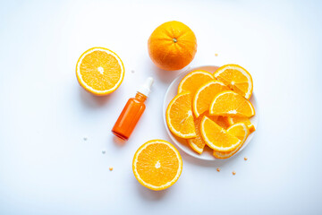 Vitamin C face skin care cosmetic concept - organic serum in a bottle and orange slices on white background.