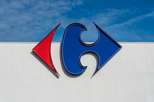 Anglet, France - 26 avril 2023: Logo du groupe Carrefour sur un fond de mur blanc et de ciel bleu