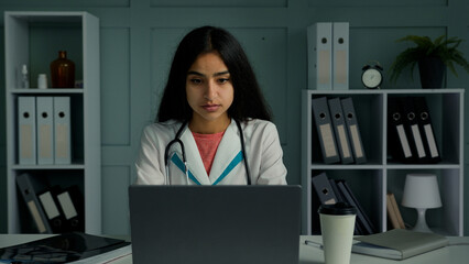 Bored young woman doctor medical intern female physician work on laptop check patients test results online in virtual medicine app typing electronic prescription make scientific research on computer